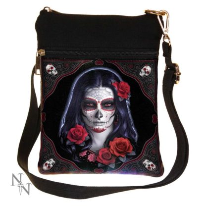 A shoulder bag made of canvas with a sugar skull woman with long back hair, and decorated with red roses. There's a top section and a front pocket.